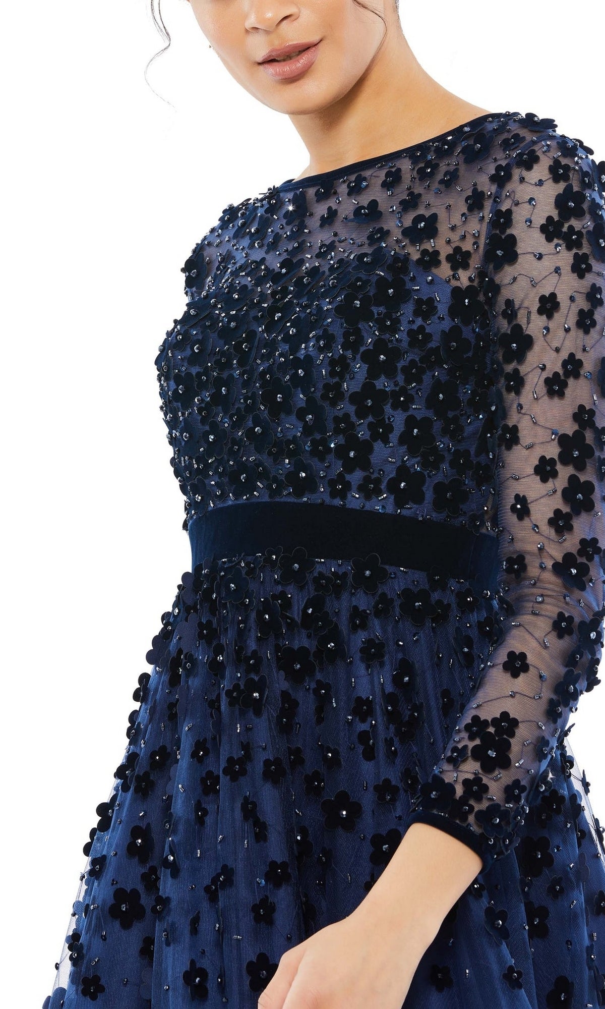 Woman in the Mac Duggal 67007 knee-length wedding-guest dress featuring navy blue floral embellishments, sheer sleeves, and appliqué details, shown from shoulders to mid-thigh against a white background.